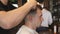 Arms of barber trimming hair of client in salon. Male hands of hairdresser combing and cutting hair of customer with