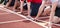 Arms and hands of four boys on their mark at the starting line on a red track