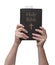 Arms raised into the air with hands reaching up and holding the Holy Bible book