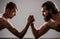 Arms wrestling thin hand, big strong arm in studio. Two man`s hands clasped arm wrestling, strong and weak, unequal