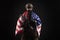 Army of america. A soldier in military equipment with a gun holds the USA flag on a black background, American special forces