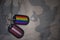 army blank, dog tag with flag of latvia and gay rainbow flag on the khaki texture background.