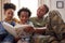 Army Mother In Uniform Home On Leave With Children Reading Book On Sofa Together