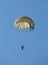 Army paratrooper floating to the ground below a parachute