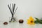 Aroma sticks in a glass cubic vase with essential oils. White background. Yellow Jerusalem artichoke flower on the table