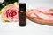 Aromatherapy composition. Bottle of rose essential oil with rose bud, rose petals and burning candle