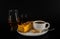 Aromatic black coffee in white cup with cheesecake on white saucer, single malt, and coffee liqueur, brown sugar, teaspoon, black