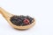 aromatic black dry tea with raspberries on a wooden spoon isolated on white