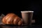 Aromatic coffee in a paper cup paired with a flaky croissant