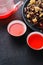 Aromatic fresh brew natural red fruit tea in two bowls ,glass teapot, wooden scoop with dry tea leaves,glass jar and plate on a