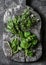 Aromatic garden herbs, food ingredients, seasonings - sage, thyme, mint, tarragon on a wooden rustic chopping board on a dark