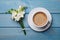 Aromatic morning coffee and flowers on light blue wooden table, flat lay