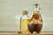 Aromatic oil in a glass jar and bottle with pistachio in bowl on wooden table, close-up