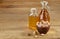 Aromatic oil in a glass jar and bottle with pistachios in bowl on wooden table, close-up.