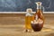 Aromatic oil in a glass jar and bottle with pistachios in bowl on wooden table, close-up.