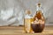 Aromatic oil in a glass jar and bottle with pistachios in bowl on wooden table, close-up.