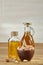 Aromatic oil in a glass jar and bottle with pistachios in bowl on wooden table, close-up.