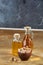 Aromatic oil in a glass jar and bottle with pistachios in bowl on wooden table, close-up.