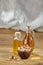 Aromatic oil in a glass jar and bottle with pistacios in bowl on wooden table, close-up, vertical.