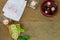 Aromatic oil in grunge wooden bowl, burned candle, pink flowers, sliced lime, green leaf, white towel on vintage stone background