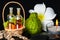 Aromatic spa concept of bottles essential oil in basket, flower, bergamot, candles and black zen basalt stones with dew