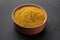 Aromatic turmeric powder in wooden bowl on dark background