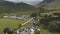 Arran whiskey distillery aerial. Road in green mountains valley. Scottish village with houses, camp