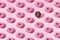 Arranged small pink and chocolate ring donuts with pink and chocolate glaze and white and brown crumbs on a pink pastel