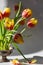 Arrangement of red and yellow tulip flowers on pin frog in vintage vase. Spring ikebana decor with japanese kenzan.