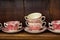 Array of delicate porcelain teacups and saucers displayed on a wooden shelf