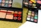 An array of makeup or cosmetics scattered over a gold glitter background. Shallow depth of field puts emphasis on lipsticks.