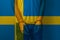 Arrested man with cuffed hands wearing shirt with Swedish flag