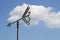 Arrow shape weathervane against summer`s sky with cumulus and paragliders in background, italian Alps. Italy