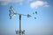 Arrow shape weathervane against summer`s sky with cumulus and paragliders in background, italian Alps. Italy