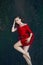 Art beautiful romantic portrait of a sexy young woman in a red dress lying in a river with green algae in summer in