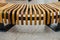 Art bench made strips of wood. Modern style chair. Long seat. Brown and yellow.