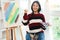 The art concept, Asian female artist in sweater smiling to happy after painting artwork success