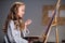 An art school student mixes colors on a palette for her canvas drawing in a workshop.