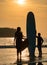 Art Silhouette Smart Asian Couple  Man and Woman, a romantic shot with Standed Surboard on beach with sunset behind them