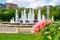 Artesian fountain in a Bucharest city park Alexandru Ioan Cuza park/IOR with coral/pink roses and a building in the back