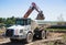 Articulated dump truck and an excavator standing behind it at a construction site while loading soil