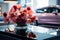 Artificial blooms adorn a glass table in a sleek car showroom.