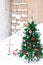 Artificial fir tree decorated with Christmas red toys outdoors in yard in snowy background with dwarf, bag with gifts