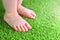 Artificial grass background. Tender foots of a baby on a green artificial turf.