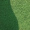 Artificial grass fake turf synthetic lawn field macro closeup, gentle shaded shadow area, green sports astroturf texture, vertical