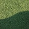 Artificial grass fake turf synthetic lawn field macro closeup with gentle shaded shadow area, green sports texture background