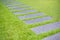 Artificial green grass walk way with concrete plate background