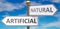 Artificial and natural as different choices in life - pictured as words Artificial, natural on road signs pointing at opposite