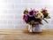Artificial pink roses flowers in vase on wooden and space wallpaper