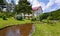 An artificial shallow pond amid a green lawn lined on the shore with stones flowing downwards against the background of